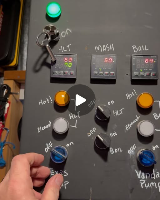 The Brewshed control panel: HLT, Mash, and Boil temperature controllers over hand-labeled element and pump switches, a hand reaching for the Texas Pump beside the Vandal Pump.