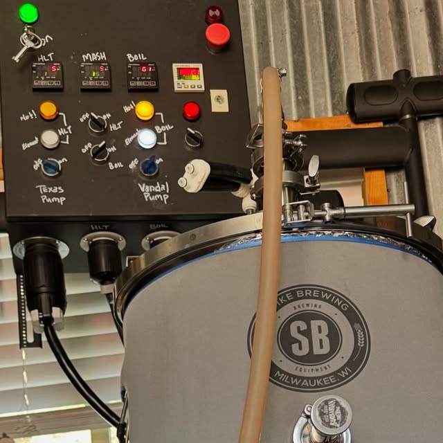 The brew rig in the shed: the labeled control panel alongside a Spike Brewing kettle and transfer hose.